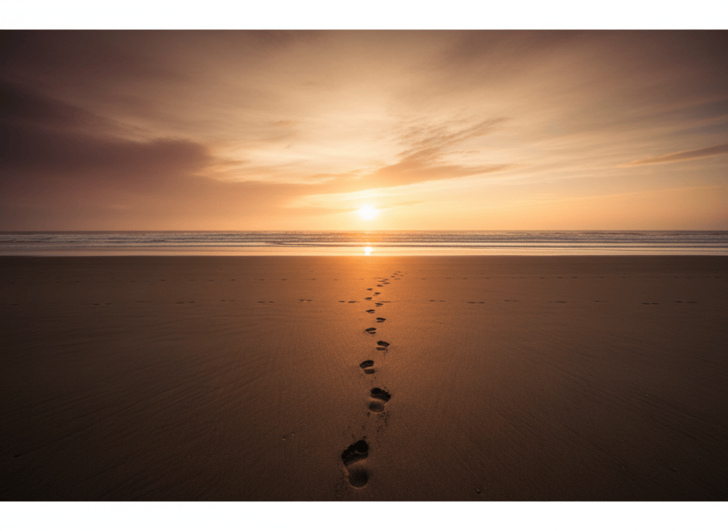 A single set of footprints along a quiet shoreline at golden hour